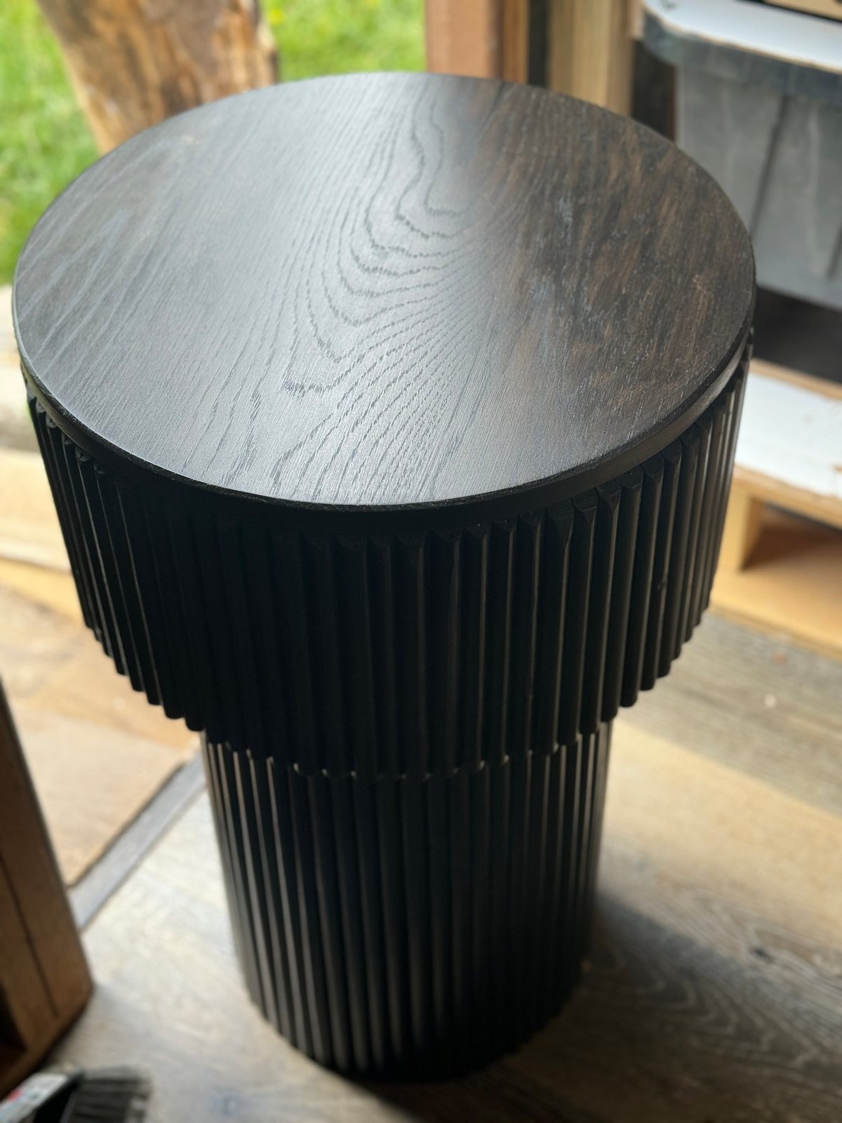 Round end table with a fluted cylinder base in ebonized white oak